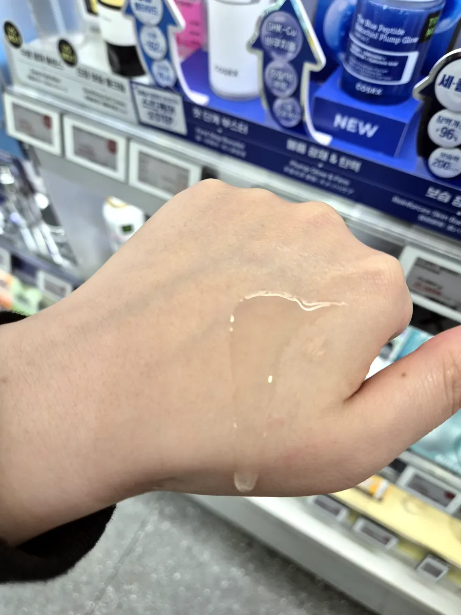 COSRX Niacinamide 15 serum swatch on the back of the hand, clear watery texture
